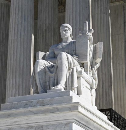 a white marble statue out front of the U.S. Supreme Court